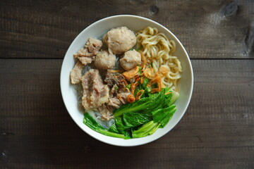 a bowl of meatball soup with vegetables in a wooden background 