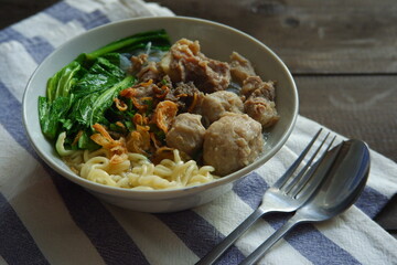a bowl of meatball soup with vegetables in a wooden background 