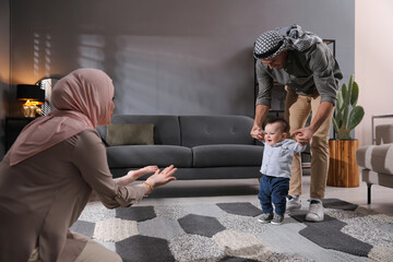 Happy Muslim family with little son in living room