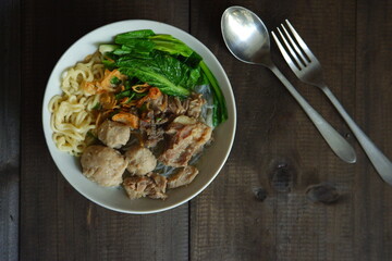 a bowl of meatball soup with vegetables in a wooden background 