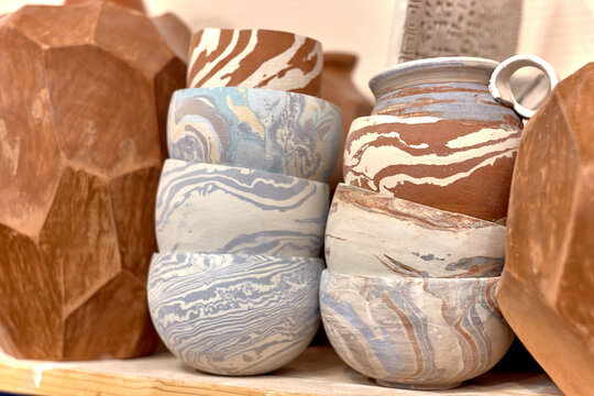 A stack of ready-made ceramics using Japanese technique Nerikomi made of white, red and blue clay dries on a shelf