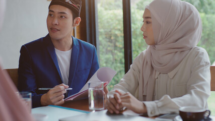Upwardly mobile Asian Muslim business entrepreneur SME start up group of young man and women, discussing sale and marketing analysis, Asian Muslim SME teamwork e-commerce concept