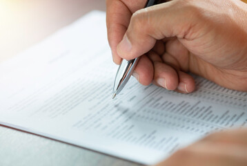 Close-up of Hand using writing pen with questionnaire or paperwork survey question filling in...