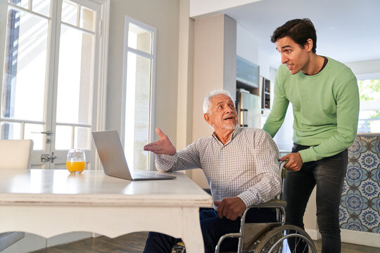 Curious senior in wheelchair at laptop computer