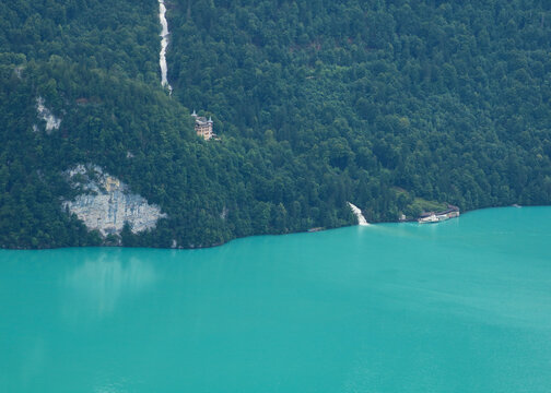 Giessbach Falls and historic hotel. Ship waiting at the shore of turquoise Lake Brienz.