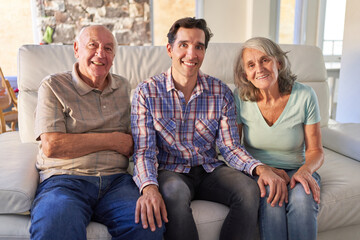 Senior parents and son sit together on the sofa