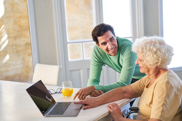 Obraz na płótnie Canvas Young man helping senior mother on laptop computer