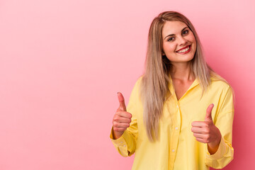 Young russian woman isolated on pink background smiling and raising thumb up