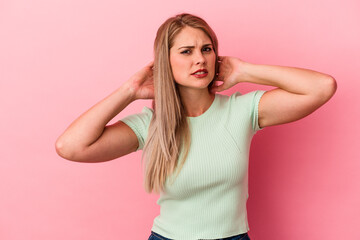 Young russian woman isolated on pink background touching back of head, thinking and making a choice.