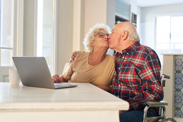 Happy senior couple kissing on laptop