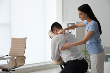 Man receiving massage in modern chair indoors