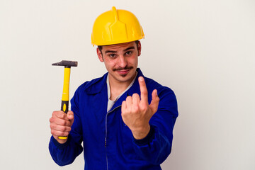 Young caucasian worker man holding a hammer isolated on white background pointing with finger at you as if inviting come closer.