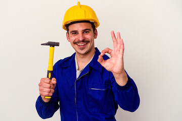Young caucasian worker man holding a hammer isolated on white background cheerful and confident...