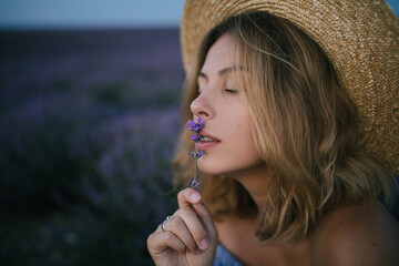 Young beautiful woman wearing straw hat in a lavender field.