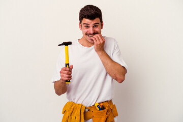 Young caucasian worker man with tools isolated on white background biting fingernails, nervous and...