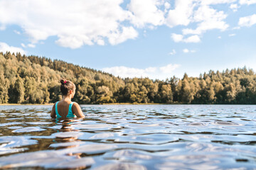 Lake in Finland. Woman swimming. Finnish nature, water and serene sky in summer. Outdoor bathing in...