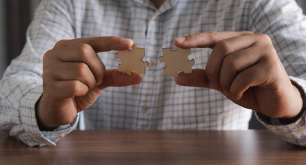 Close up hand businessman  holding blank puzzle jigsaw pieces. Teamwork success and strategy concept, cooperation business solutions think or new idea, Security help support management, copy space.
