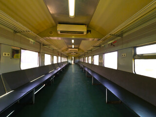 The photo looks inside from the aisle of the local Indonesian train which has a side seat