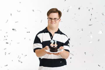 Young man with down syndrome smiling while showing birthday cake