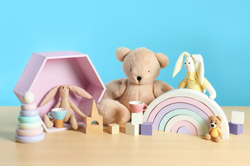 Many different toys on wooden table against light blue background