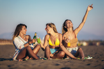 Group of young women friends drinking together on the beach