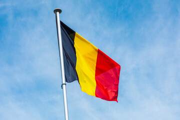 belgian flag on a pole against blue sky