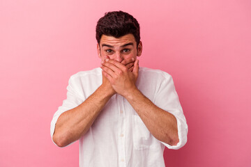 Young caucasian man isolated on pink background shocked covering mouth with hands.