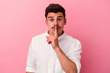 Young caucasian man isolated on pink background keeping a secret or asking for silence.