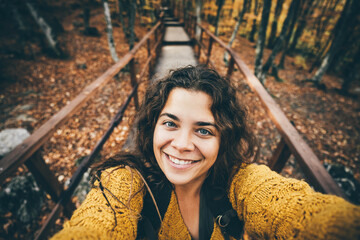 Traveler woman in yellow sweater takes selfie for travel blog.