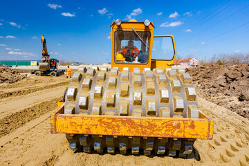 Road roller with spikes is working at construction site