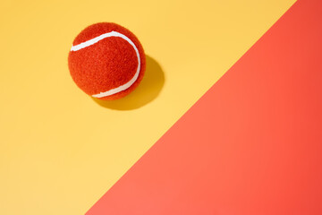 an orange tennis ball on a yellow and orange background.sport.abstract.copy space