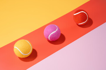 three yellow, pink and orange tennis balls on a colourful background.sport.abstract.