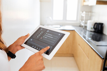 Hands of woman using application on tablet computer when setting temperature and light in kitchen