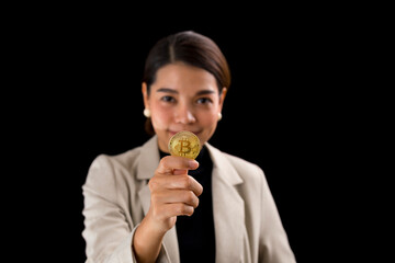 cheerful asian young woman standing on black wall background holding bitcoin looking camera.