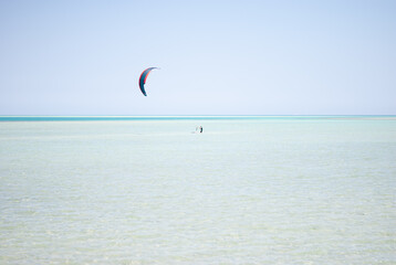 The man at the sea is engaged in kitesurfing. A lone kiter goes in for sports.