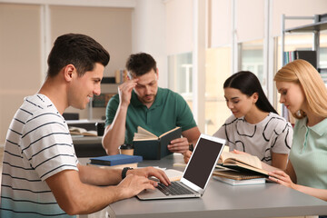 Young people discussing group project at table in library