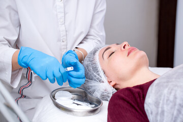 Lip augmentation. Beautician injects hyaluronic acid into the lips of a girl with a syringe. The...