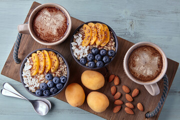 Oatmeal with blueberries and apricots, fruits, nuts and coffee
