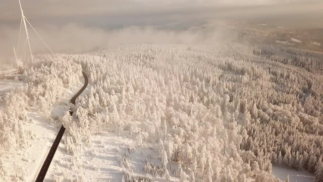 Dlog Drone view of the Feldberg Taunus Schmitten area during a cold winter day. Trees covered in snow and ice. Forrest in snow. Filmed during sunrise. Snow is wonderfully coloured in orange and red.