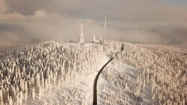 Dlog Drone view of the Feldberg Taunus Schmitten area during a cold winter day. Trees covered in snow and ice. Forrest in snow. Filmed during sunrise. Snow is wonderfully coloured in orange and red.
