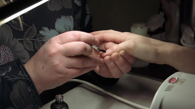 Female manicure applying red nail polish