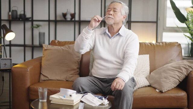Asian elderly man self test for COVID-19 at home with Antigen test kit.
