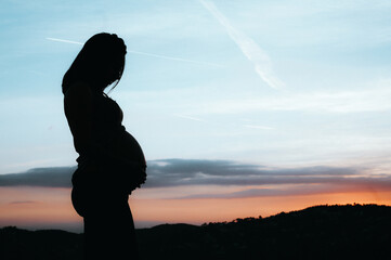 silhouette of a pregnant girl with a sunset background