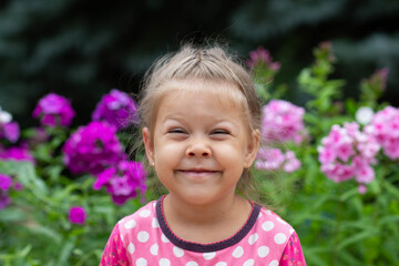 Portrait of funny caucasian girl of four years old looking at camera in the summer park