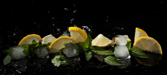 Mint, lemon and ice in splashes of water on a dark background