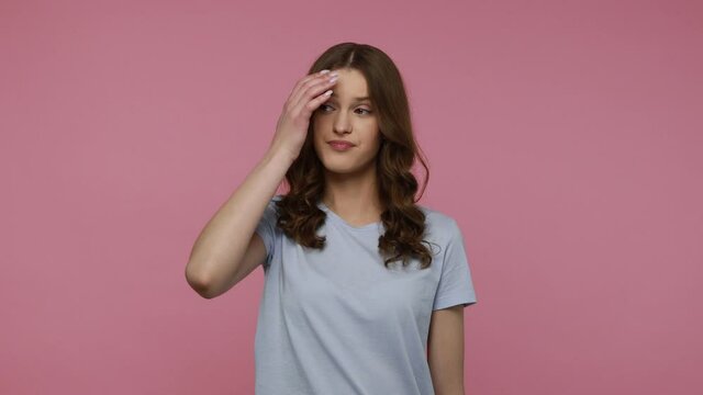 Pensive young woman with dark wavy hair in casual T-shirt solving serious problem in mind, thinking over smart idea, pondering and musing answer.Indoor studio shot isolated over pink background.
