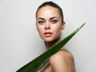 pretty woman with aloe leaf on light background makeup