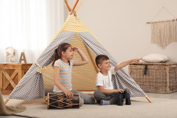 Cute little children playing in toy wigwam at home © New Africa