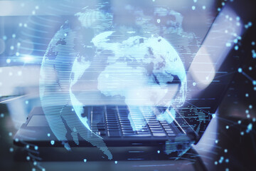 Close up of laptop with abstract globe interface on blurry desktop background. International communication and business concept. Double exposure.