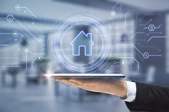 Close up of businessman hand holding tablet with creative glowing house icon on blurry office background with circuit. Remote control and smart home concept. Double exposure.
